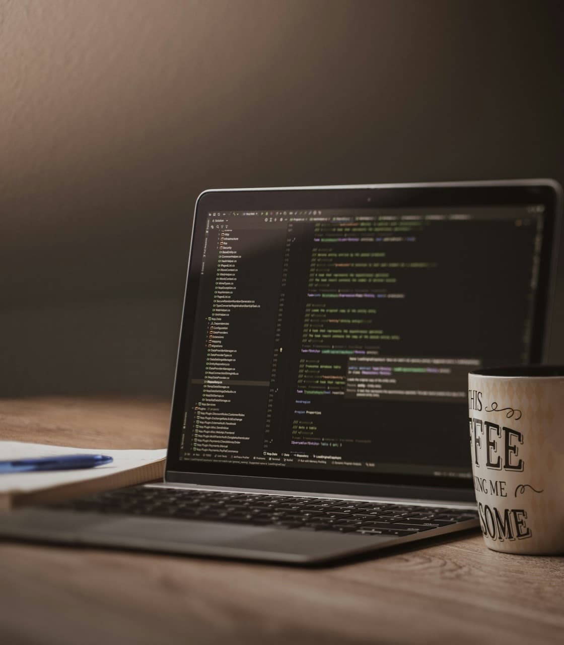 Laptop with code on the display and a coffee mug on a desk